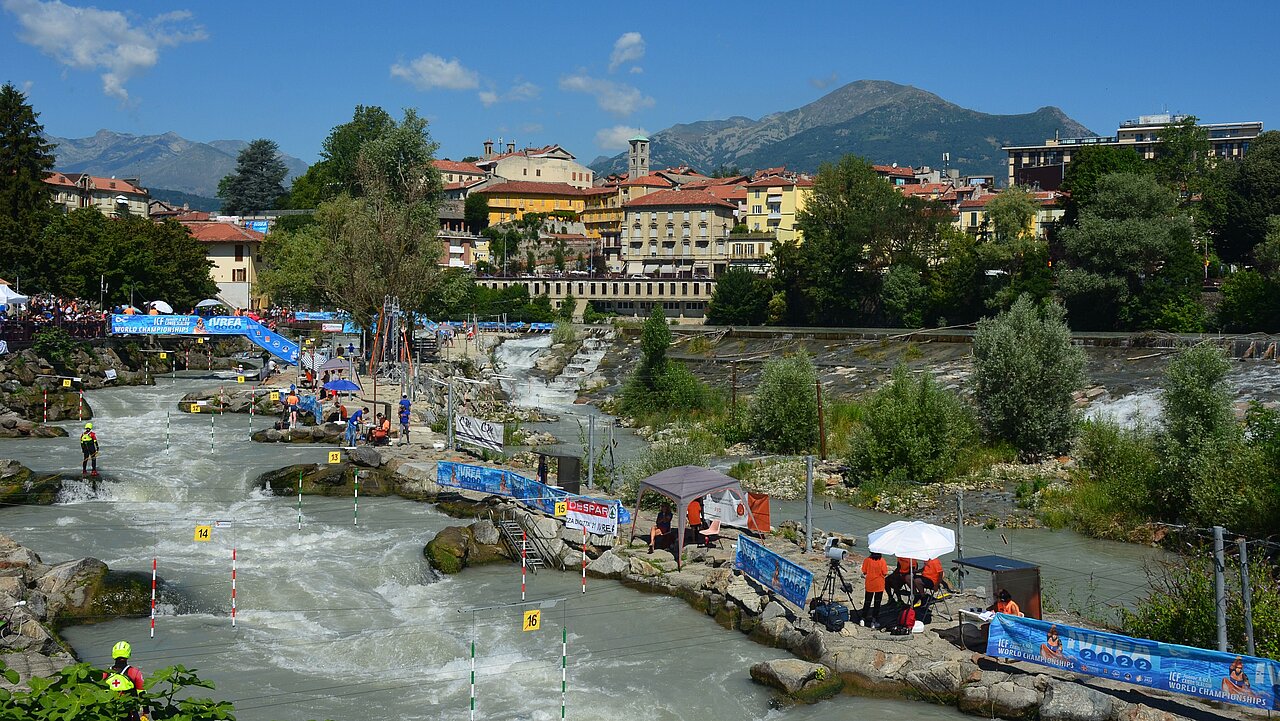 Die Kanustrecke von Ivrea im Hintergrund blauer Himmel und die Stadt mit Bergen.