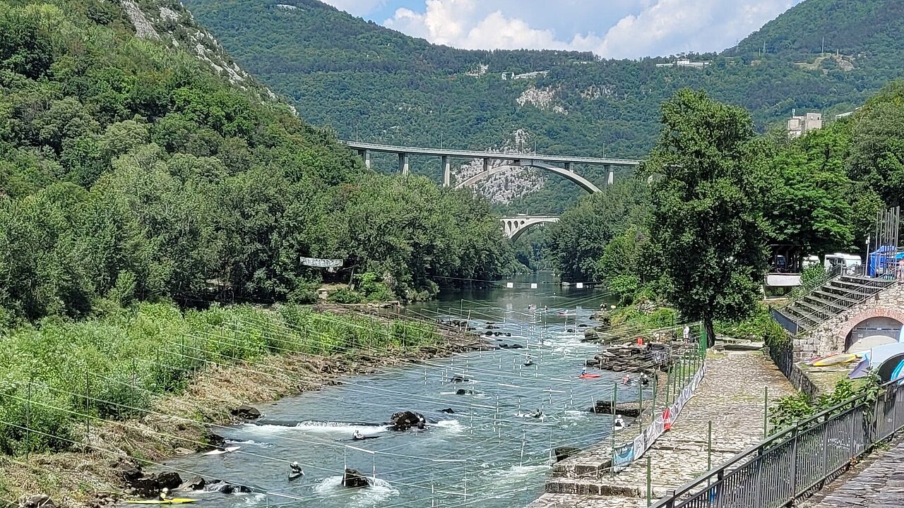 Die Kanuslalom Strecke von Solkan im Hintergrund die legendäre Brücke mit Bergen..